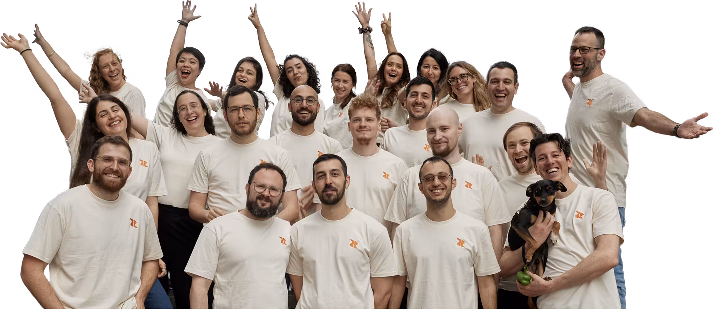 Group of diverse young adults wearing matching white t-shirts with orange logos, smiling and posing cheerfully together with one person holding a small black and brown dog.
