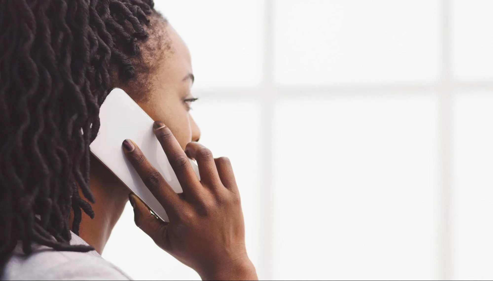 A person holding a smartphone to their ear during a captioned call.