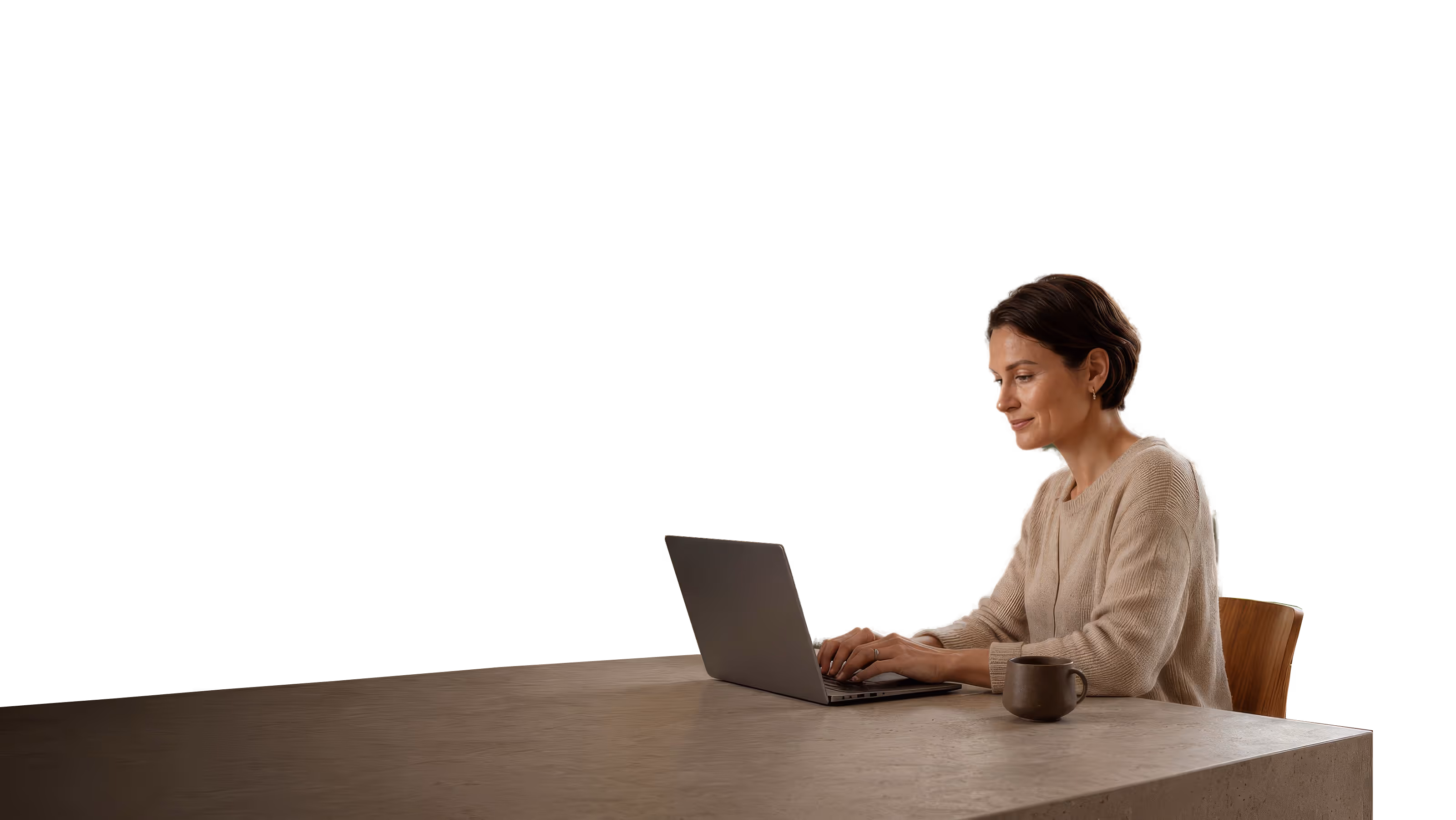 A woman sits at a stone desk with a laptop and a mug, lit by a tall window with green trees behind her.